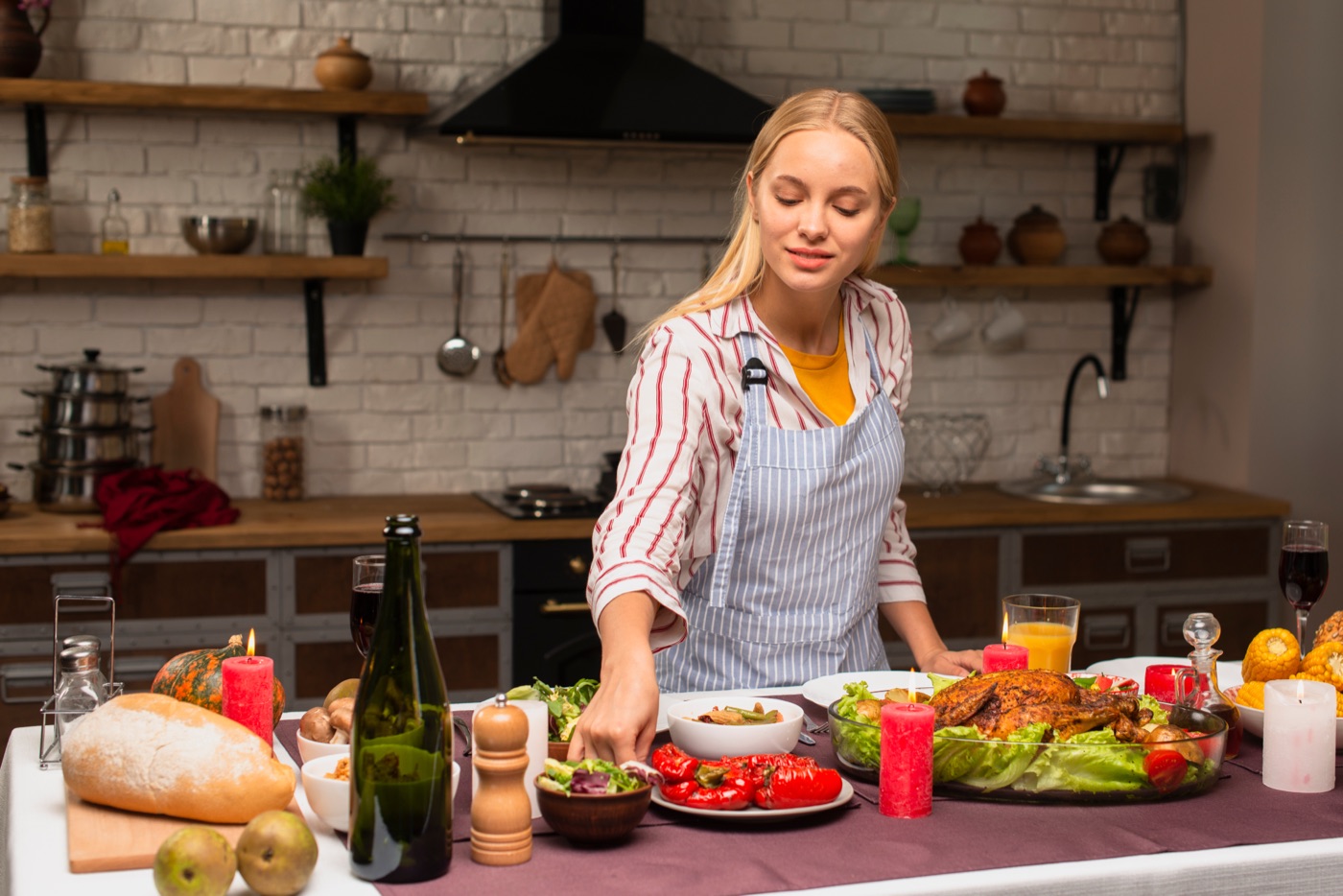 A woman in an apron sets dishes on a kitchen table