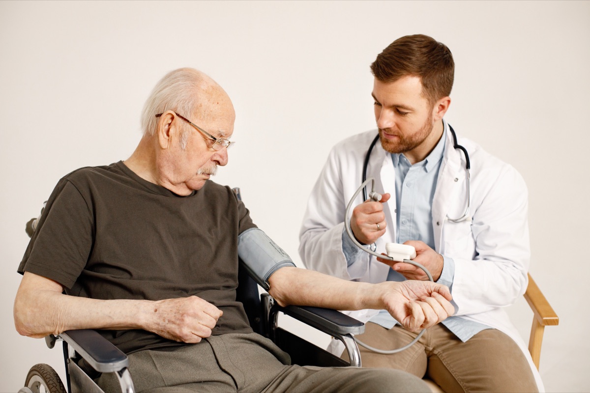 A doctor takes an older patient's blood pressure