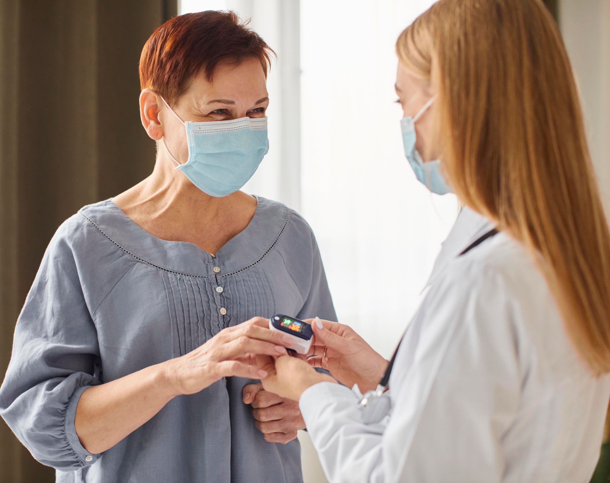 A clinician checks an older patient's blood oxygen with a fingertip pulse oximeter