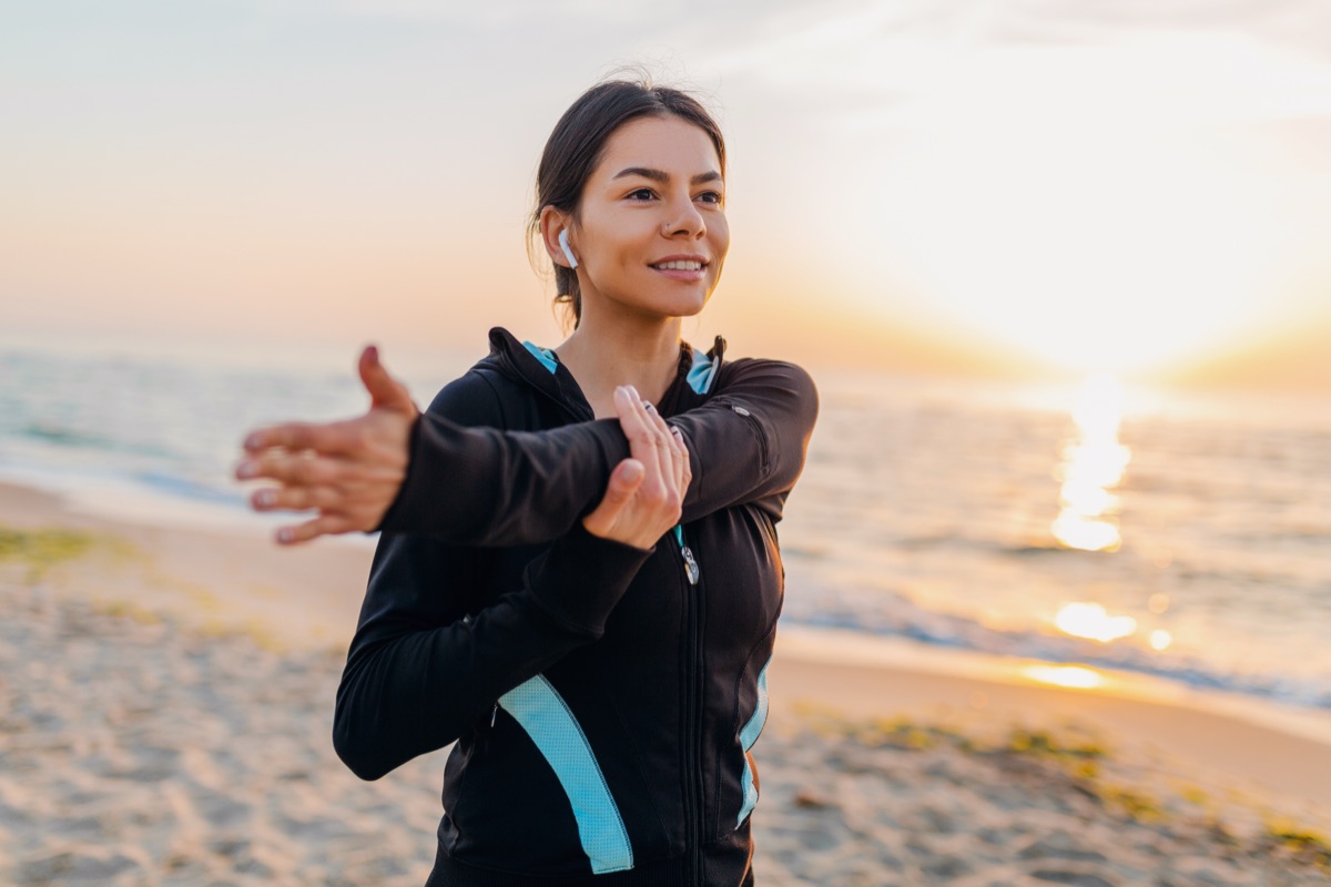 A woman stretching on a beach at sunrise