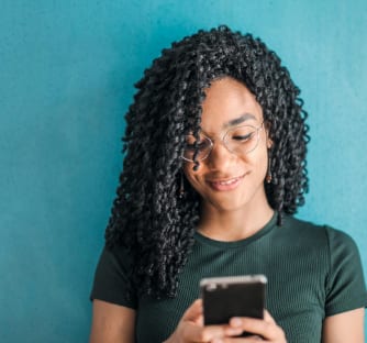 A woman smiles as she reads a text on her phone