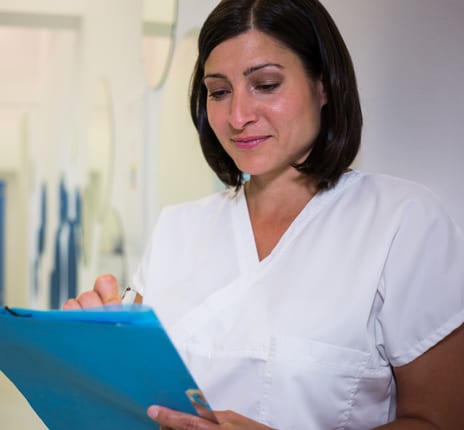 A nurse reviews notes on a clipboard